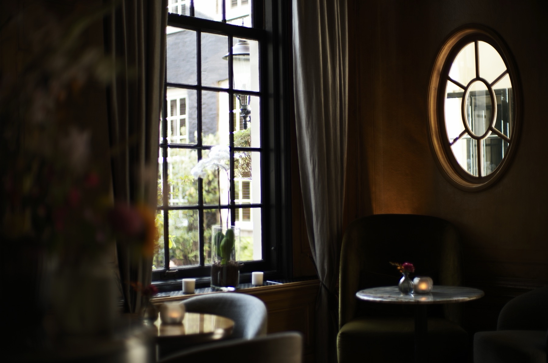 A candlelit corner of the bar at the Dylan Amsterdam, its window opening onto the courtyard