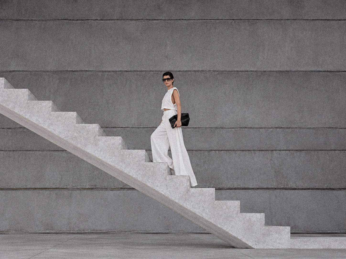 White linen wide-leg trousers and a cropped linen top on a concrete staircase