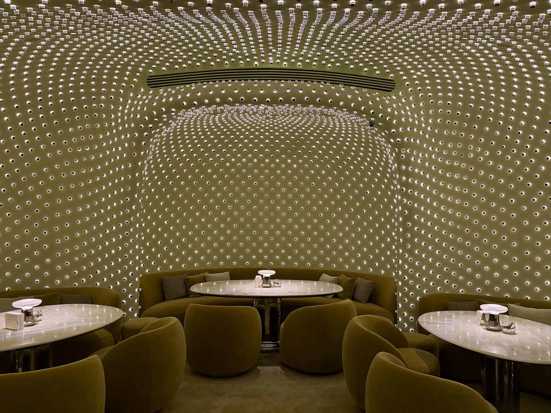 Walls of tiny lights curving over green velvet seating and marble tables at Peridot, Hong Kong